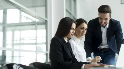 2016 Best Practices Study – What the Latest Report Says About the Industry Two businesswomen and a businessman working on a project on a laptop in a well lit conference room.