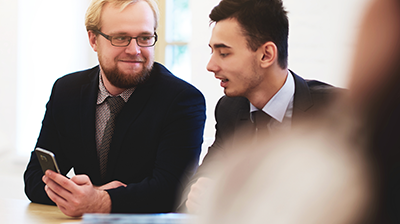 Applied Mobile: Add Prospects A man showing a colleague something on his phone