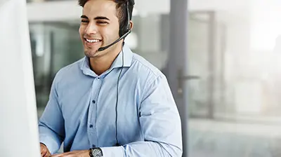 Purge the Paper: 6 Benefits of Going Paperless Now A man wearing a headset and smiling while working on his computer
